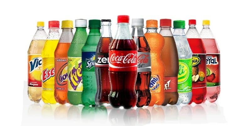Colorful assortment of carbonated soft drinks and bottled beverages, including Coca-Cola, Sprite, Fanta, and more, displayed in plastic bottles with vibrant labels.