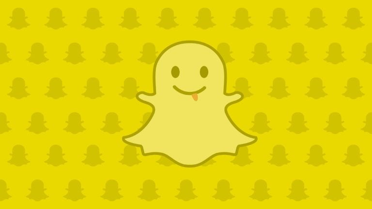Smiling ghost cartoon on yellow background with Snapchat logo pattern.
