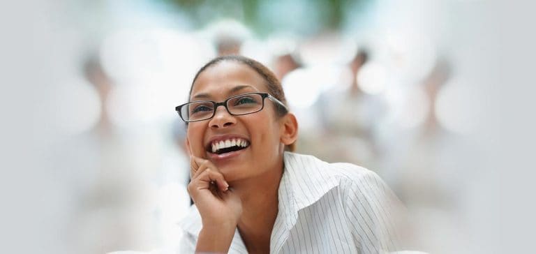 Bright smiling woman wearing glasses at a professional event, representing confidence and engagement.