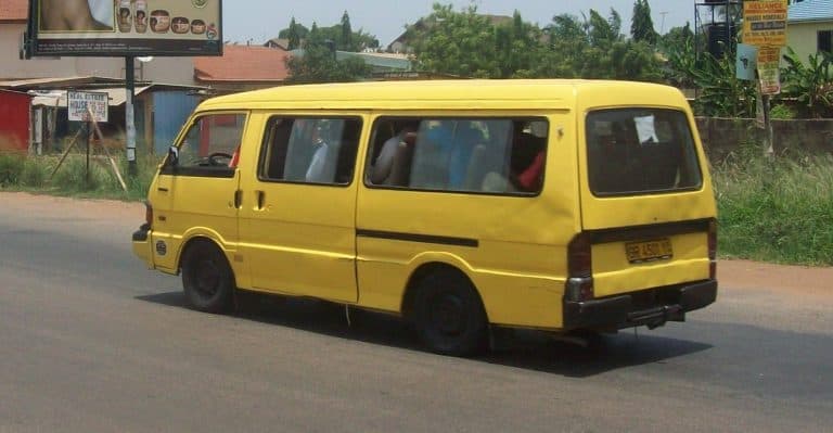 Yellow minibus on a busy road in an urban area, featuring traditional transportation in Africa with open windows and vibrant color, providing affordable travel options.
