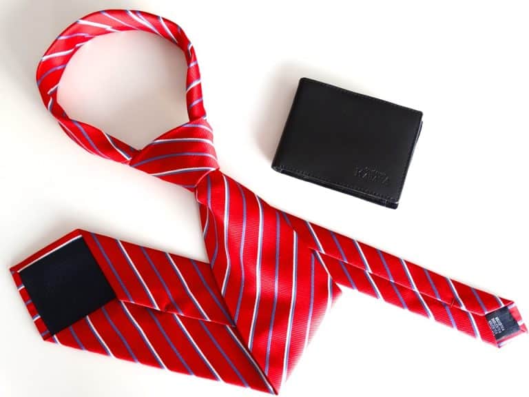 Red striped business tie, black wallet, and dark leather cardholder arranged on white background.